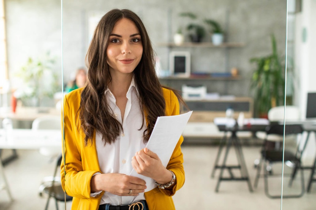 Professional woman wearing yellow blazer holding papers