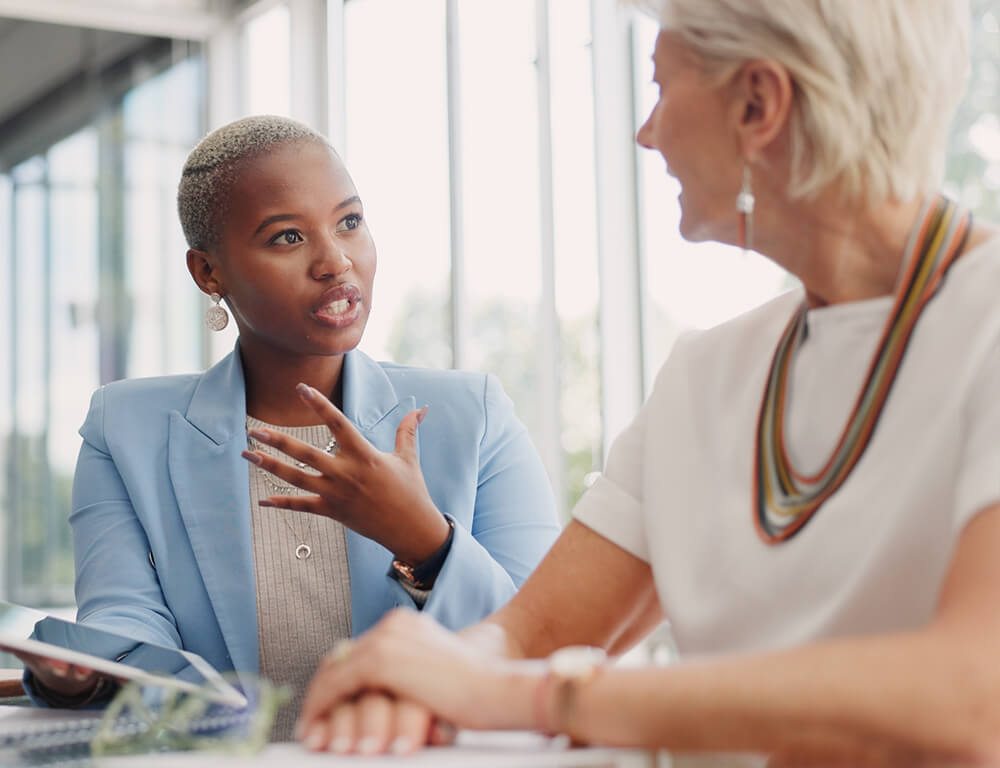 A young professional woman wearing a blue blazer meeting with an older woman