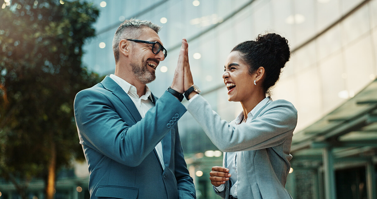 Two professional people high-fiving outside