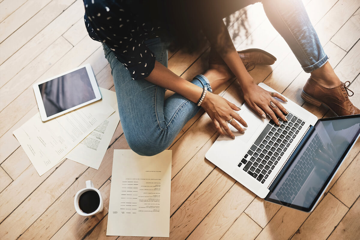 Woman sitting on the floor with her laptop and coffee